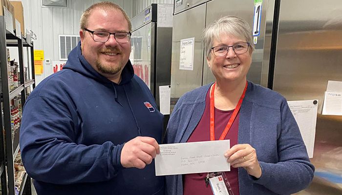 two individuals, one presenting check