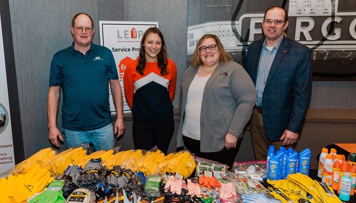 group of four people standing behind a table with donated items