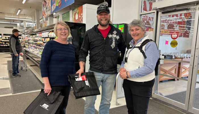group of three people in a grocery store holding bags