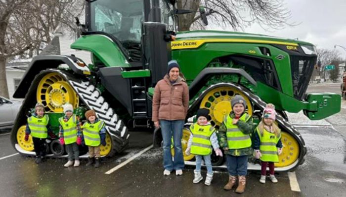 children and an adult standing in front of a tractor
