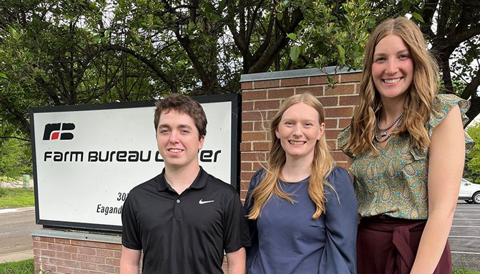 three people standing in front of Farm Bureau sign