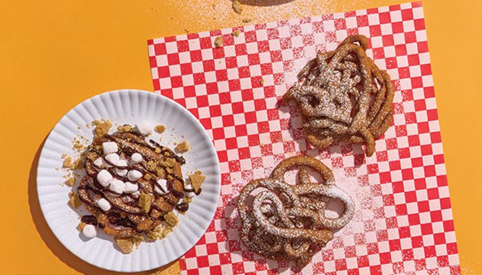 overhead photo of funnel cakes on plates and wrappers