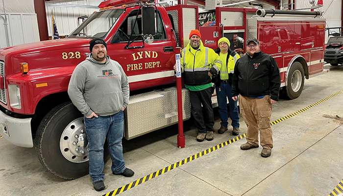 group of people standing in front of a fire truck with a grain safety auger