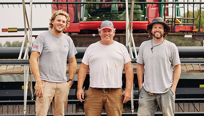 three men standing in front of a combine