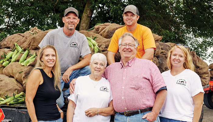 Family around sacks of sweet corn