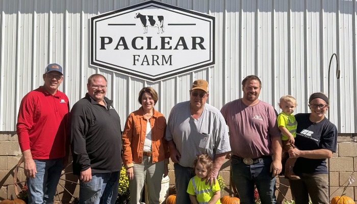 group of people standing in front of farm sign