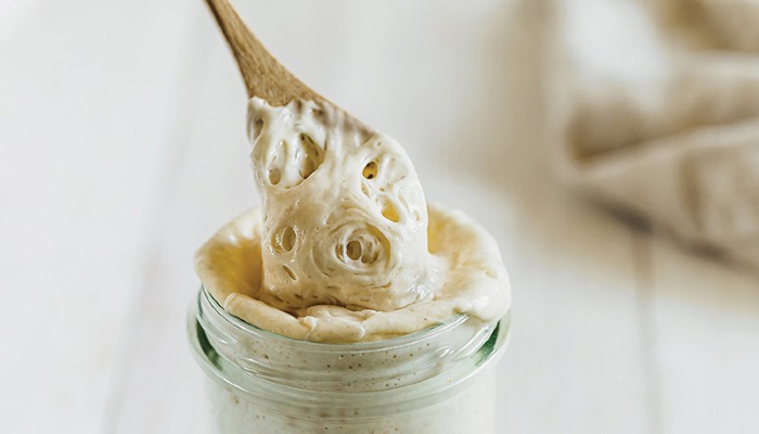 jar of sourdough starter with spoon coming out