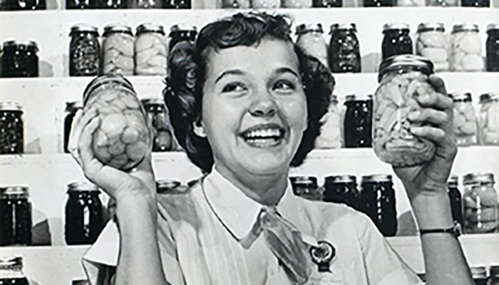 black and white photo of woman holding two canning jars