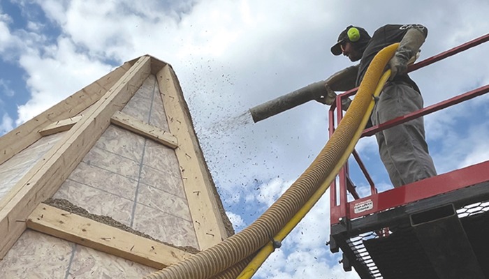man on crane lift installing hempcrete