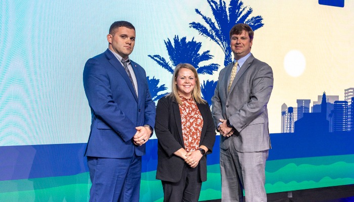 three people standing on stage for a photo