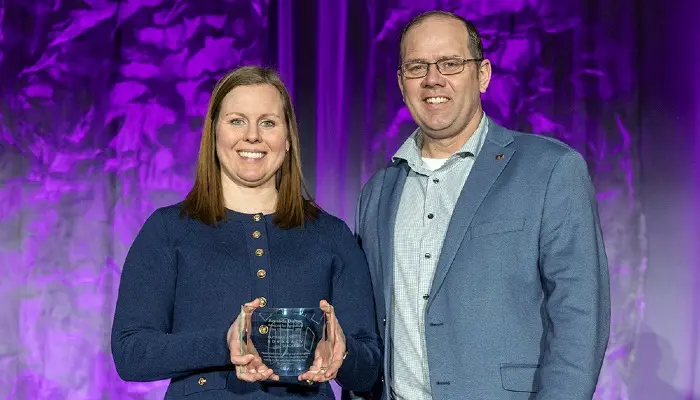 two people standing on stage with one holding an award