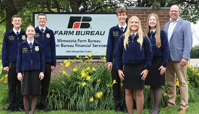 FFA officers and MFBF President Dan Glessing standing in front of sign